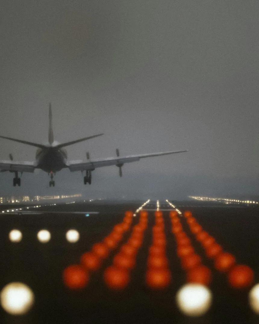 An aircraft on short finals at dusk, above the runway approach lights
